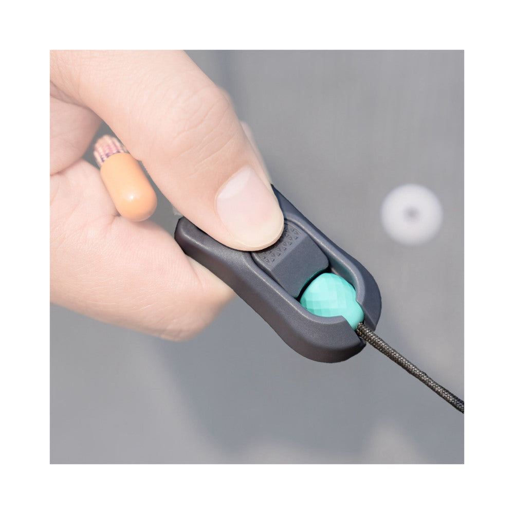 Close-up of a hand demonstrating the turquoise quick-attach connector being inserted into a black camera strap mount.