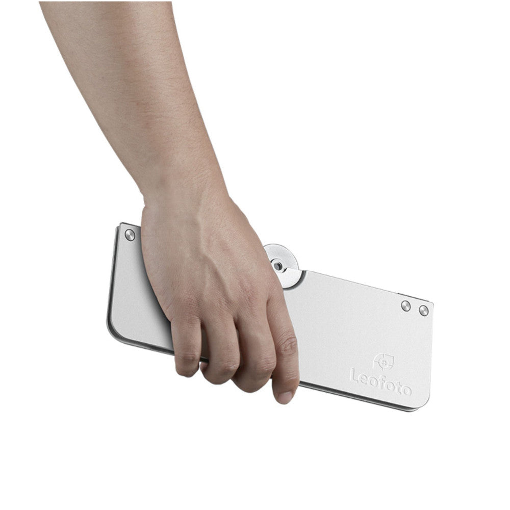 Hand holding white Leofoto LCH-1 folding tray at an angle, showing the compact rectangular design with mounting holes and branding visible.