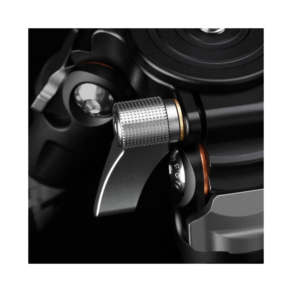 Close-up detail of carbon fiber tripod leg with metal locking mechanism and ball head attachment, black and silver finish against dark background.