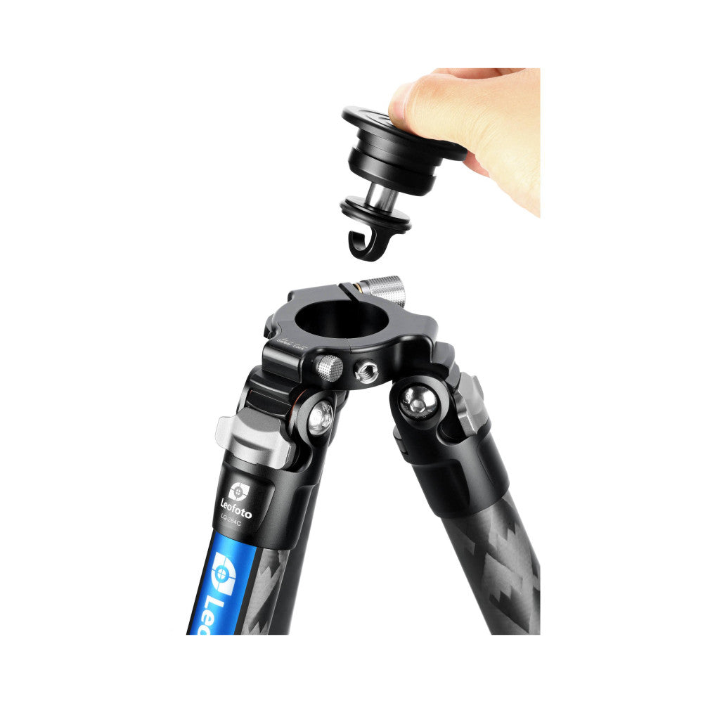 Hand holding a black ball head above an extended Leofoto carbon fiber tripod with blue leg sections, demonstrating assembly.