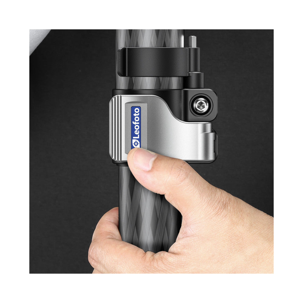 Close-up of hand holding Leofoto carbon fiber monopod with quick-release clamp mounted on top against dark background.