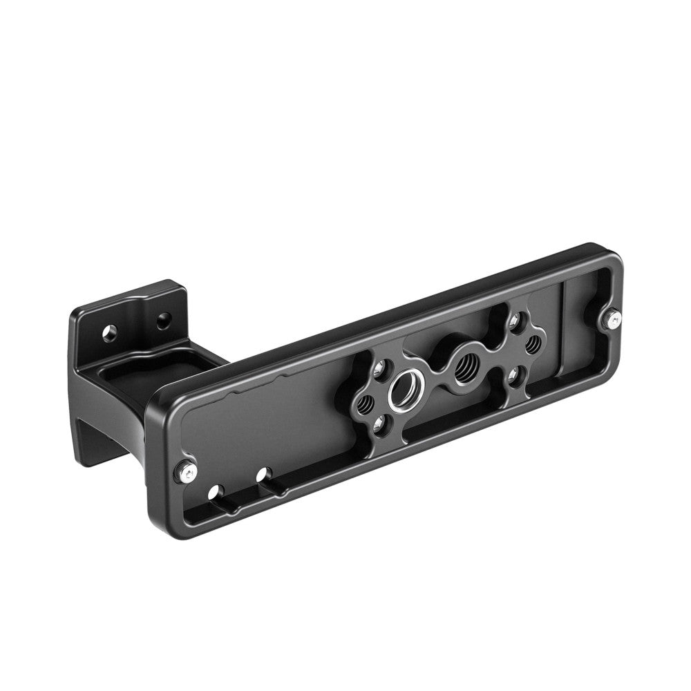 Black metal Arca lens foot shown from an angled side view, displaying threaded mounting holes and a bracket attachment point on the left end.