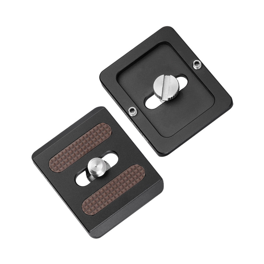 Two black Arca Swiss quick release plates shown at angle, displaying threaded knob and textured grip surfaces with metal hardware.