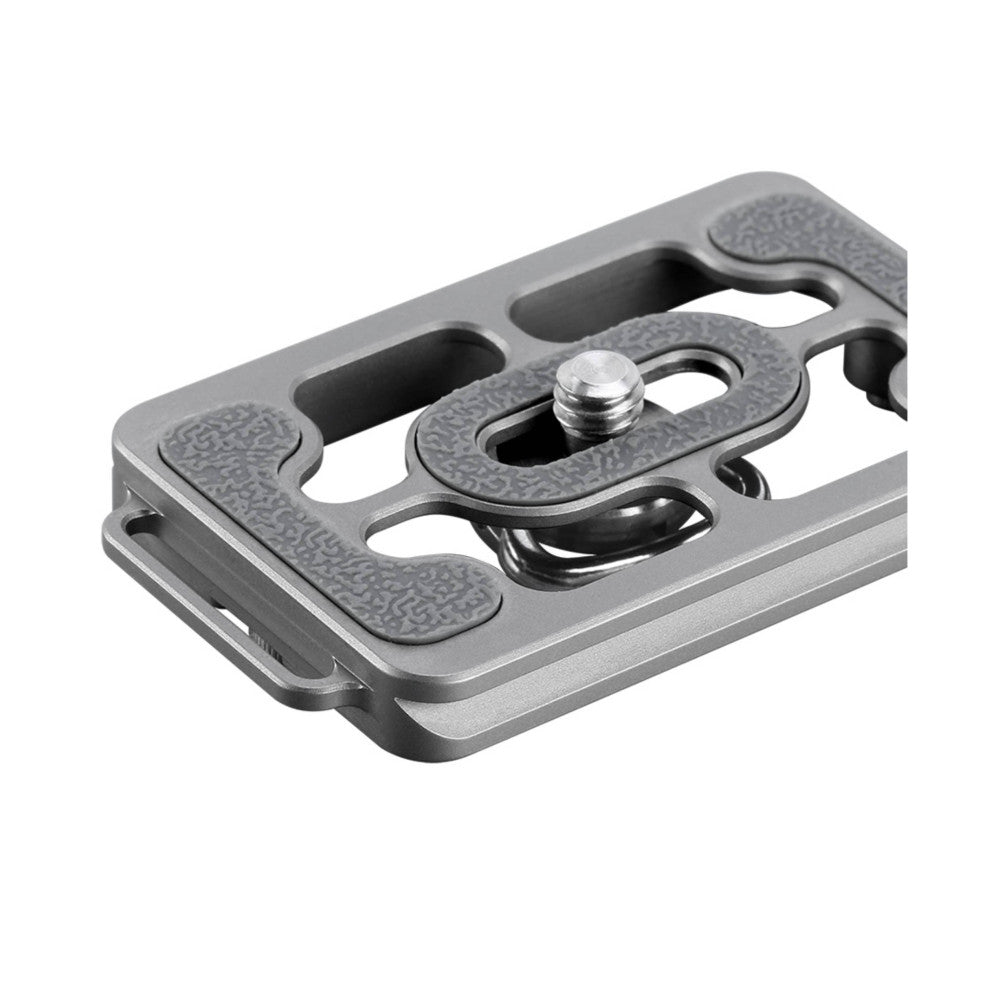 Angled overhead view of a titanium quick-release plate with textured grip pads, multiple mounting slots, and a central ball-head socket.