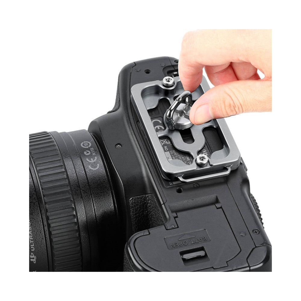 Hand demonstrating installation of titanium Arca Swiss quick release plate on camera tripod socket, close-up detail view.