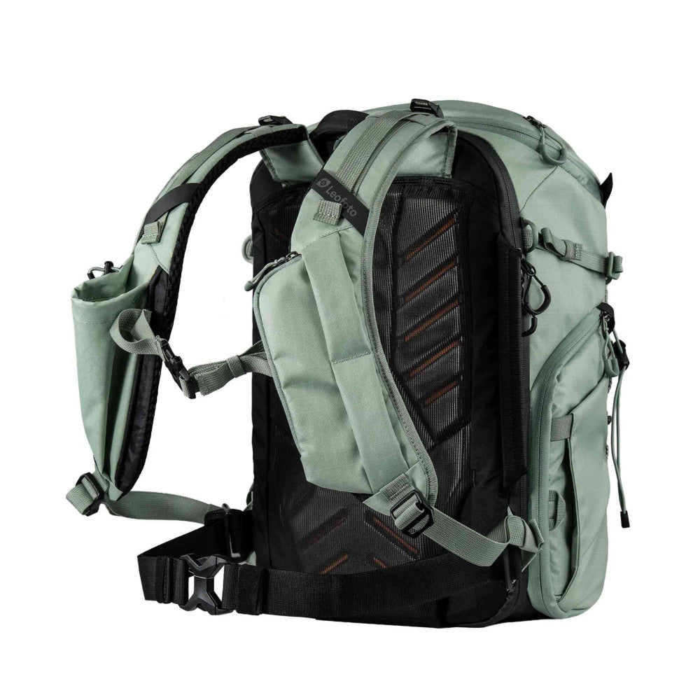 Rear view of green camera backpack with black mesh panel, shoulder straps, and hip belt visible against white background.