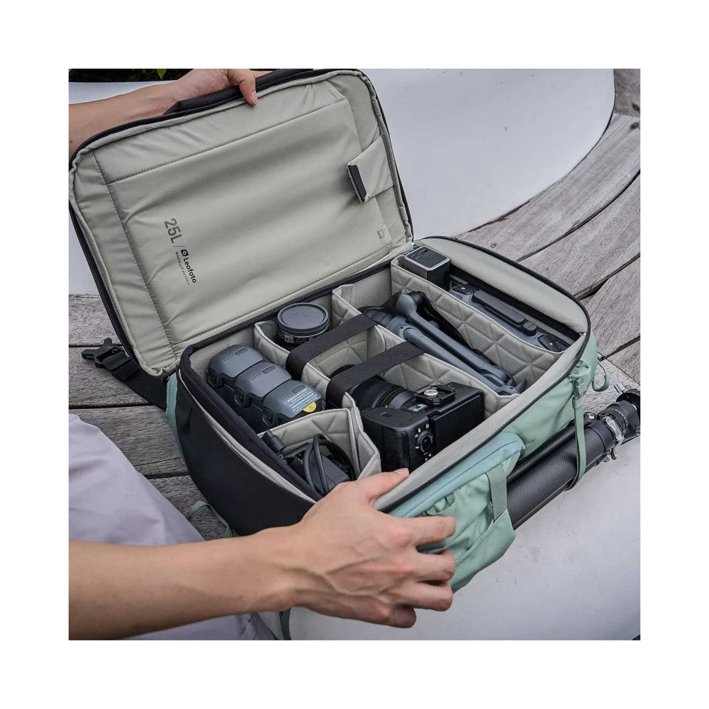 Open camera backpack displaying organized compartments with camera gear including lenses, drone, and accessories inside.