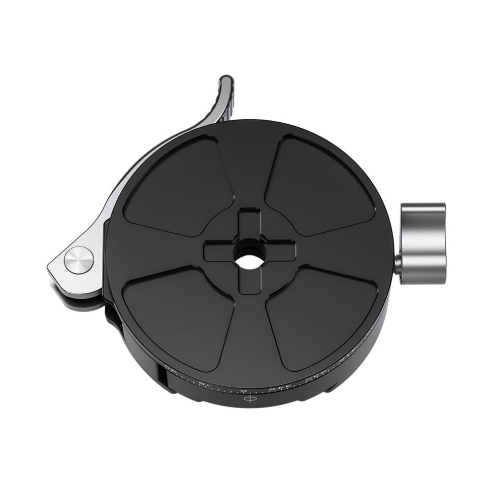 Top-down view of a black circular panning clamp with a cross-shaped center mount, lever release on the left side, and a cylindrical attachment on the right.