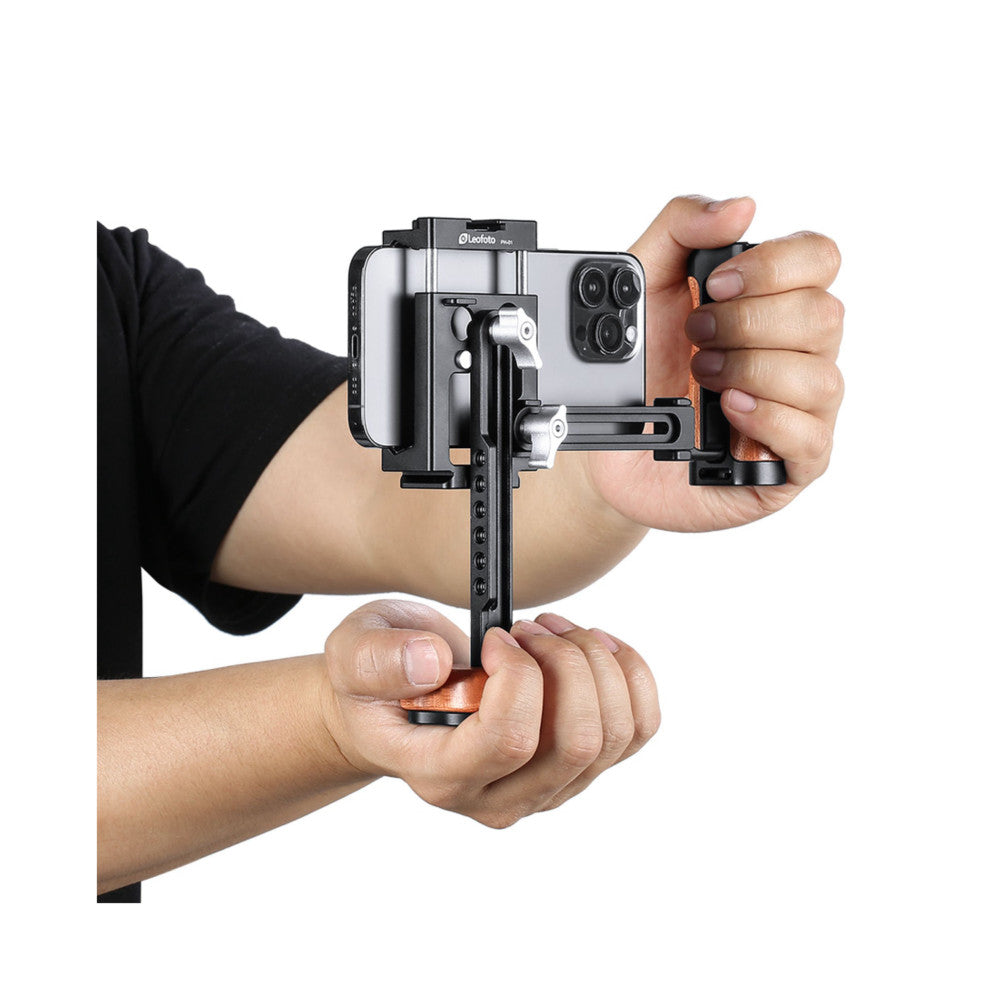 Hands holding the Leofoto PH-01 cage kit mounted on a smartphone, showing the stabilizer rig in use from the front angle.