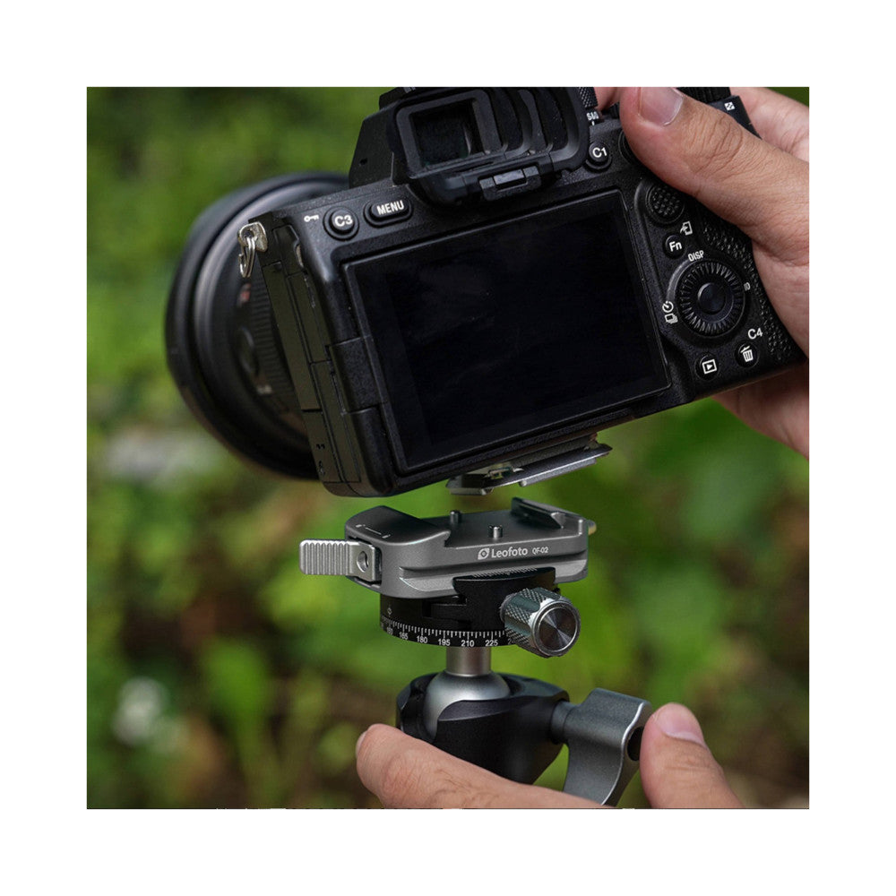Leofoto QF-02 quick release plate mounted on tripod ball head with mirrorless camera attached, shown in-use outdoors.