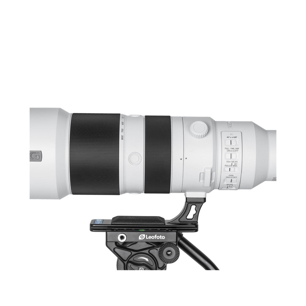 Side view of white Sony telephoto lens mounted on black Leofoto tripod foot, showing lens controls and mounting bracket detail.