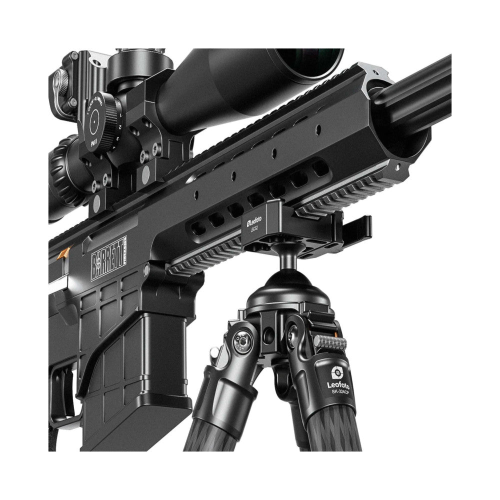 Close-up detail view of carbon fiber tripod with integrated ballhead, mounted rifle with scope and tactical rail system, shown from side angle.