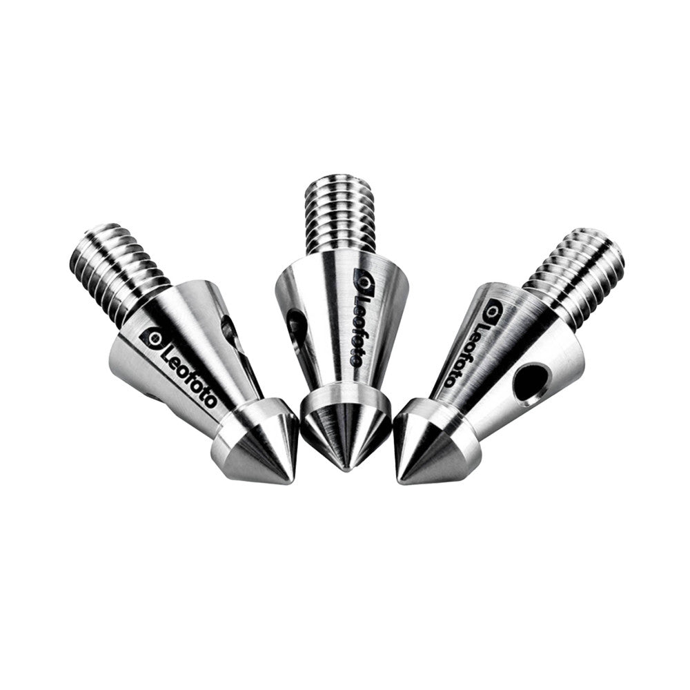 Three polished titanium tripod spikes with threaded shafts arranged in a fan pattern against a white background.