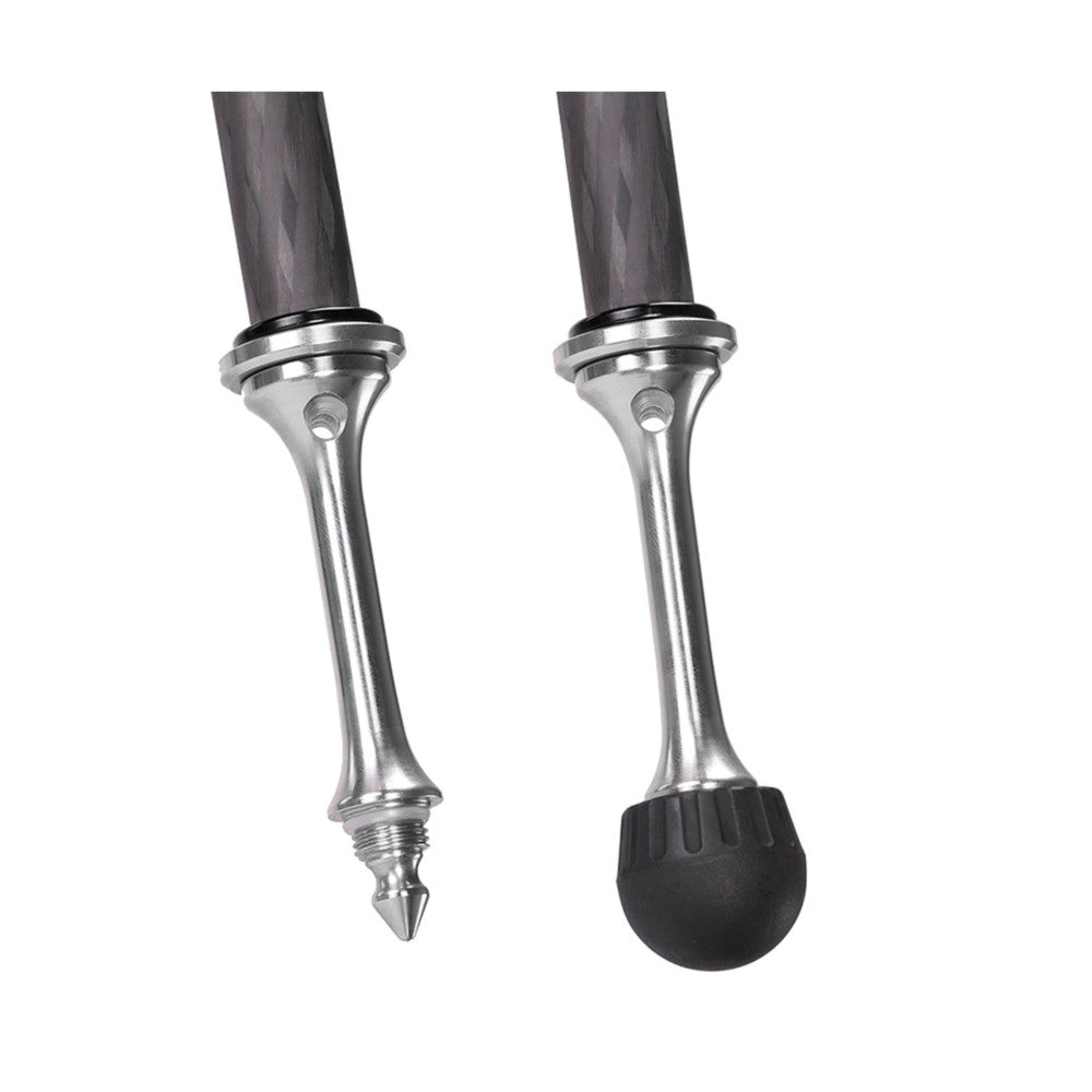 Two silver tripod feet with pointed spikes and rubber caps shown side by side against white background, close-up detail view.