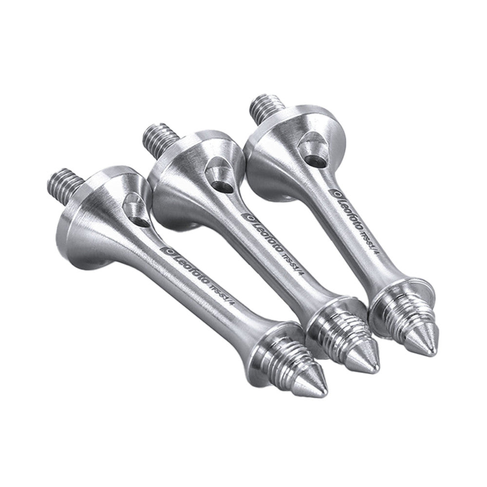 Three silver metal tripod spikes with threaded tops arranged at angles against a white background, showing conical points and mounting threads.
