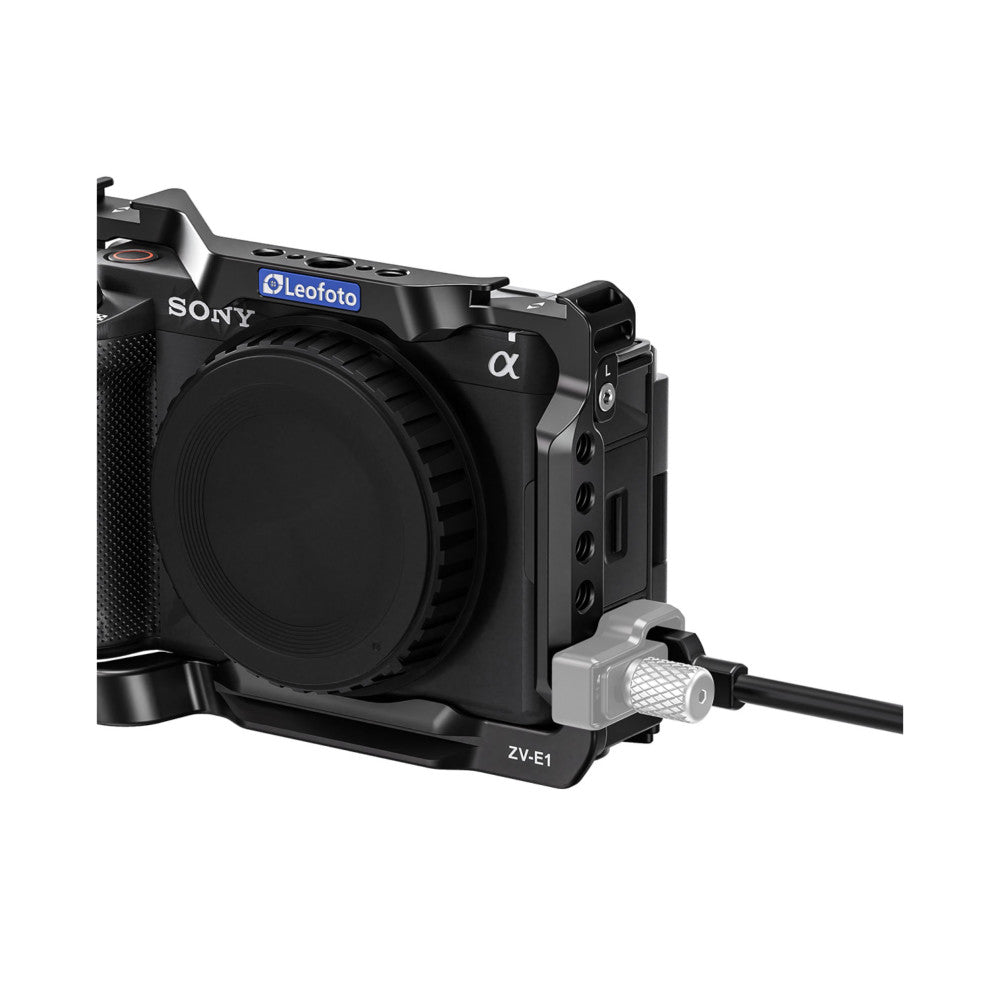 Black Sony ZV-E1 camera mounted in Leofoto ZV-E1 cage rig, shown from right side angle with cable attachment visible.