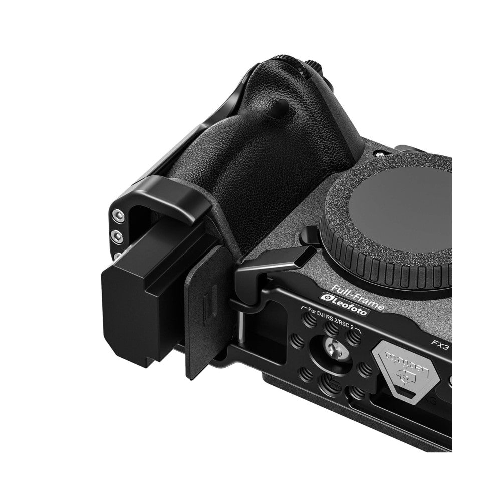 Black camera cage with textured grip shown at three-quarter angle, displaying mounting points and control access ports on bottom plate.