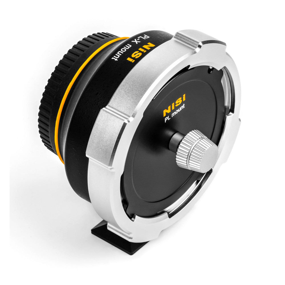 White and black lens adapter with yellow accent ring shown at angled three-quarter view, displaying the PL mount side and adjustment knob detail.