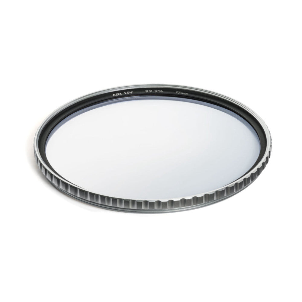 Angled overhead view of a circular UV filter showing its glass surface and ridged metal frame with text etched on the rim.
