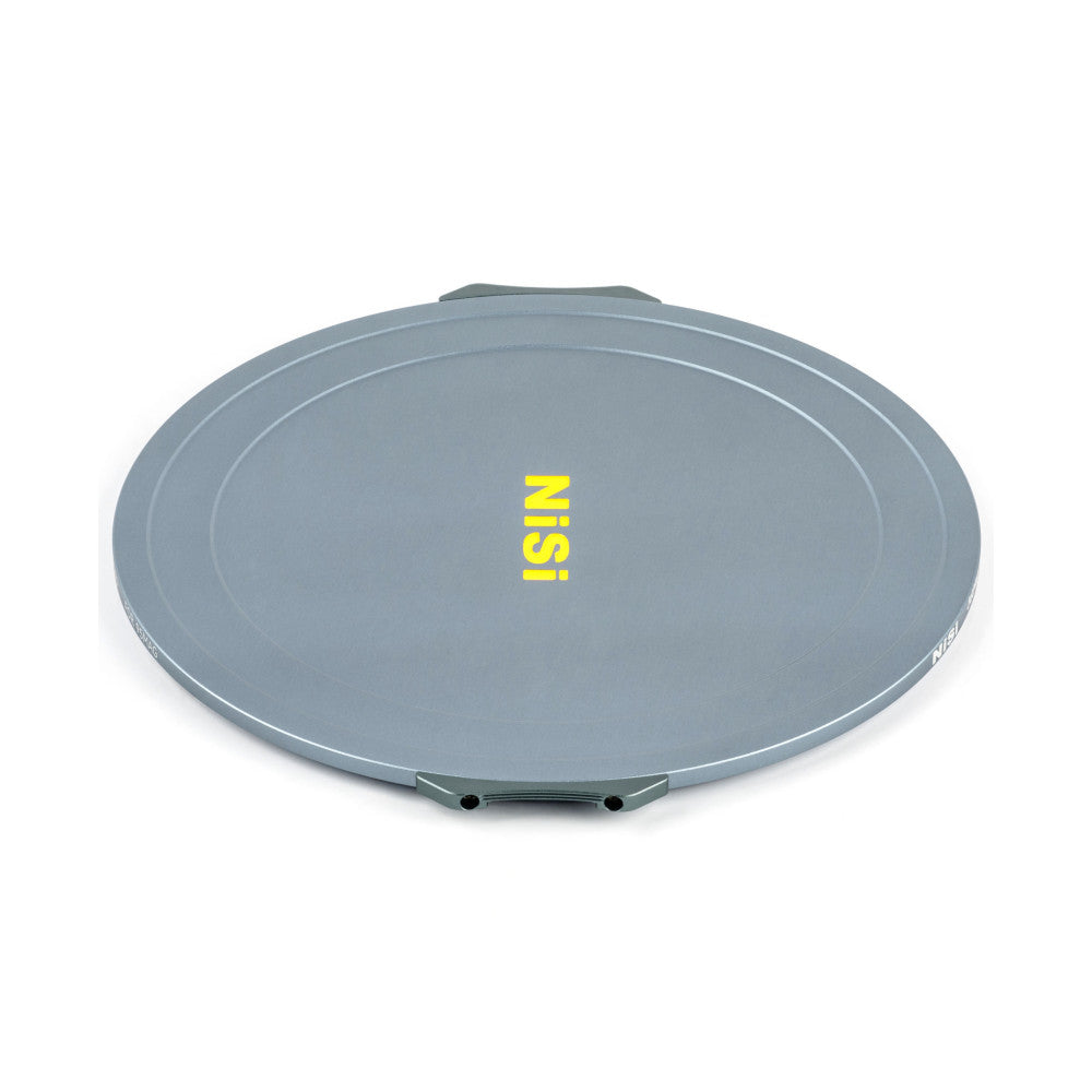 Gray circular magnetic lens cap with "NiSi" yellow text, shown at an angled perspective view displaying the flat front surface and metal mounting mechanism underneath.