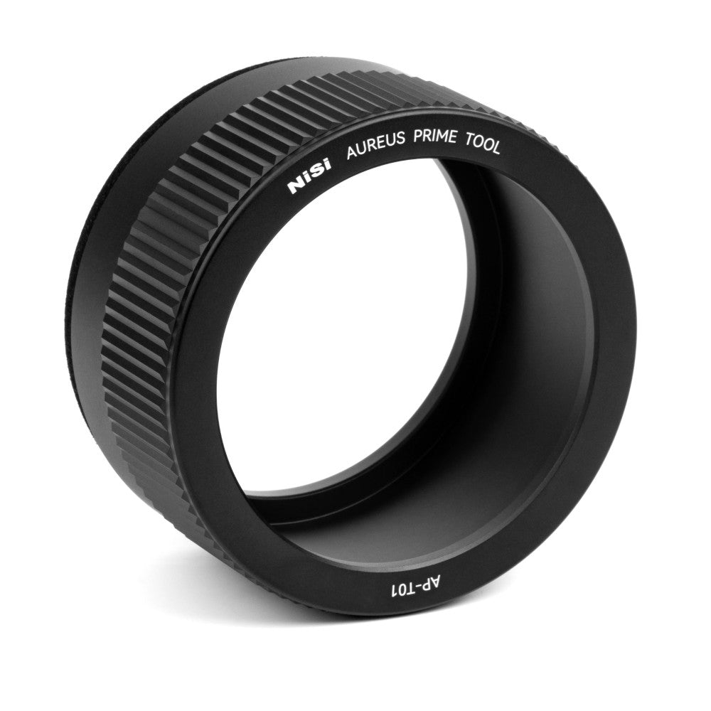 Black cylindrical lens tool with textured grip ring and branding, shown at an angled three-quarter view against white background.