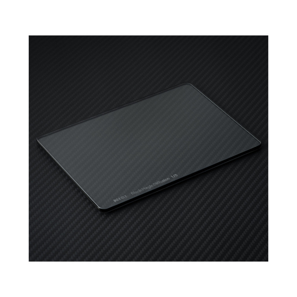 A rectangular optical filter with rounded corners photographed at an angle on a dark carbon fiber textured background, showing its glass surface and dark frame edge.