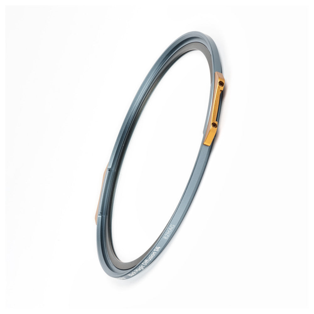 Gray circular magnetic filter with gold metal attachment piece, shown at an angle against white background.