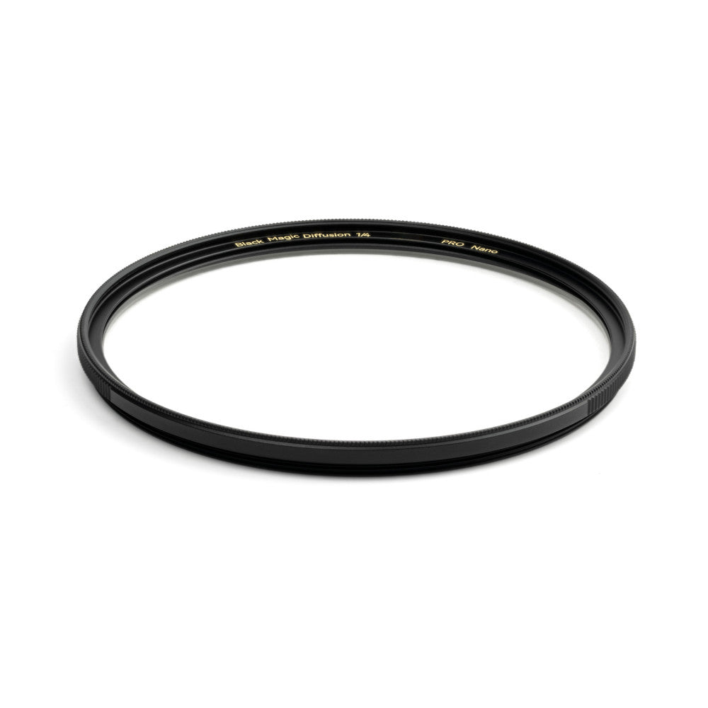 Black circular camera filter with textured edge viewed from above at an angle, showing gold text on the rim against white background.