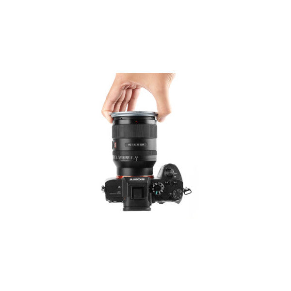 Hand holding magnetic CPL filter above Sony camera body, demonstrating attachment method