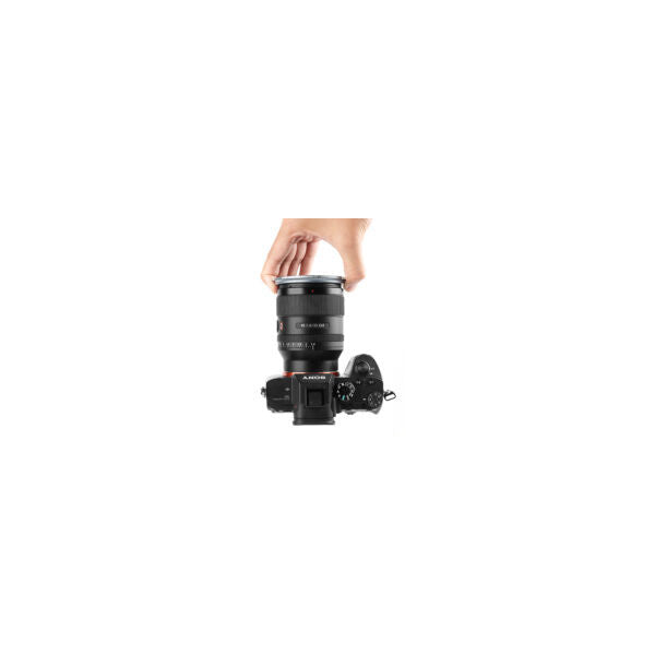 Hand holding NiSi JetMag Pro magnetic adapter ring above camera lens mounted on mirrorless camera body, demonstrating product use and scale.