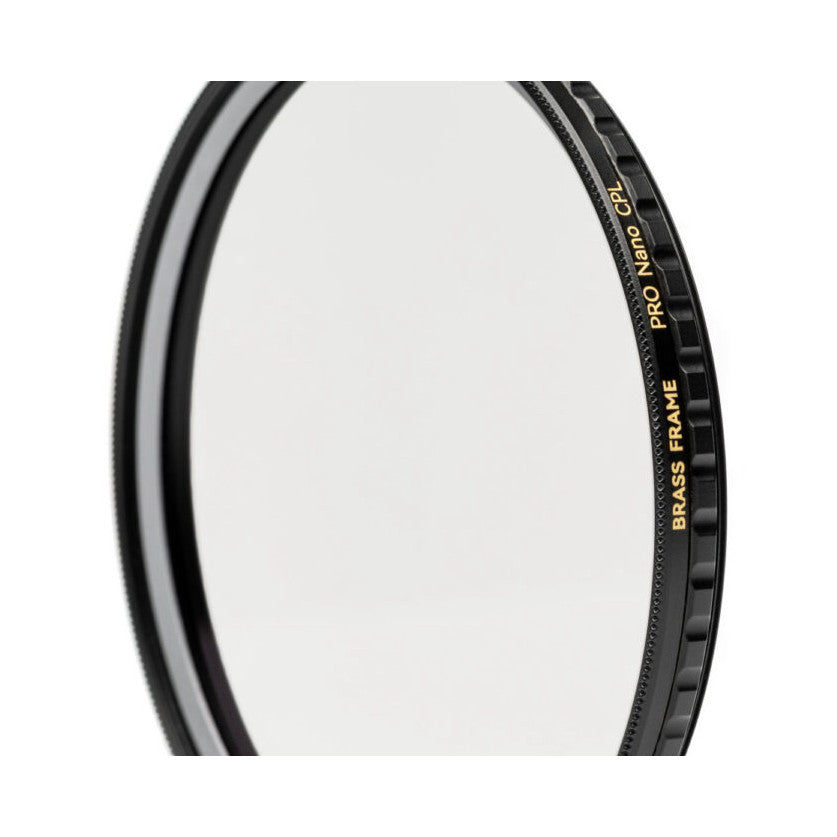 Close-up of a circular polarizing filter showing the brass frame edge with gold text and knurled grip against white background.
