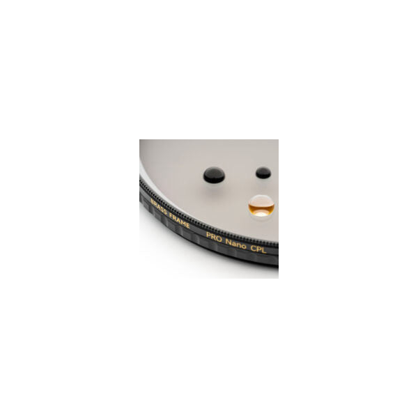 Close-up of circular polarizing filter showing brass frame edge with water beads and oil droplet demonstrating hydrophobic coating