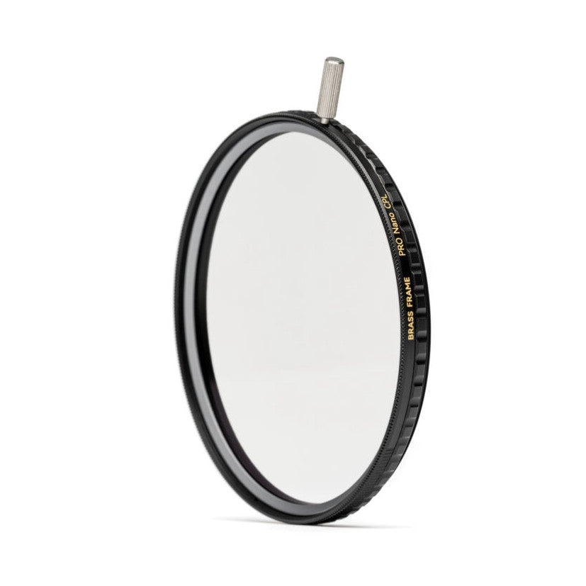 Angled side view of a circular polarizing filter with black brass frame and metal adjustment knob on top, displayed against white background.