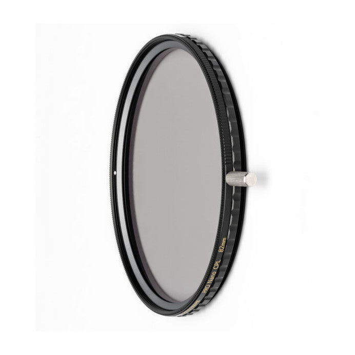 Circular polarizing filter with black frame and brass ring, shown at an angle against white background, displaying the glass lens surface and adjustment mechanism.