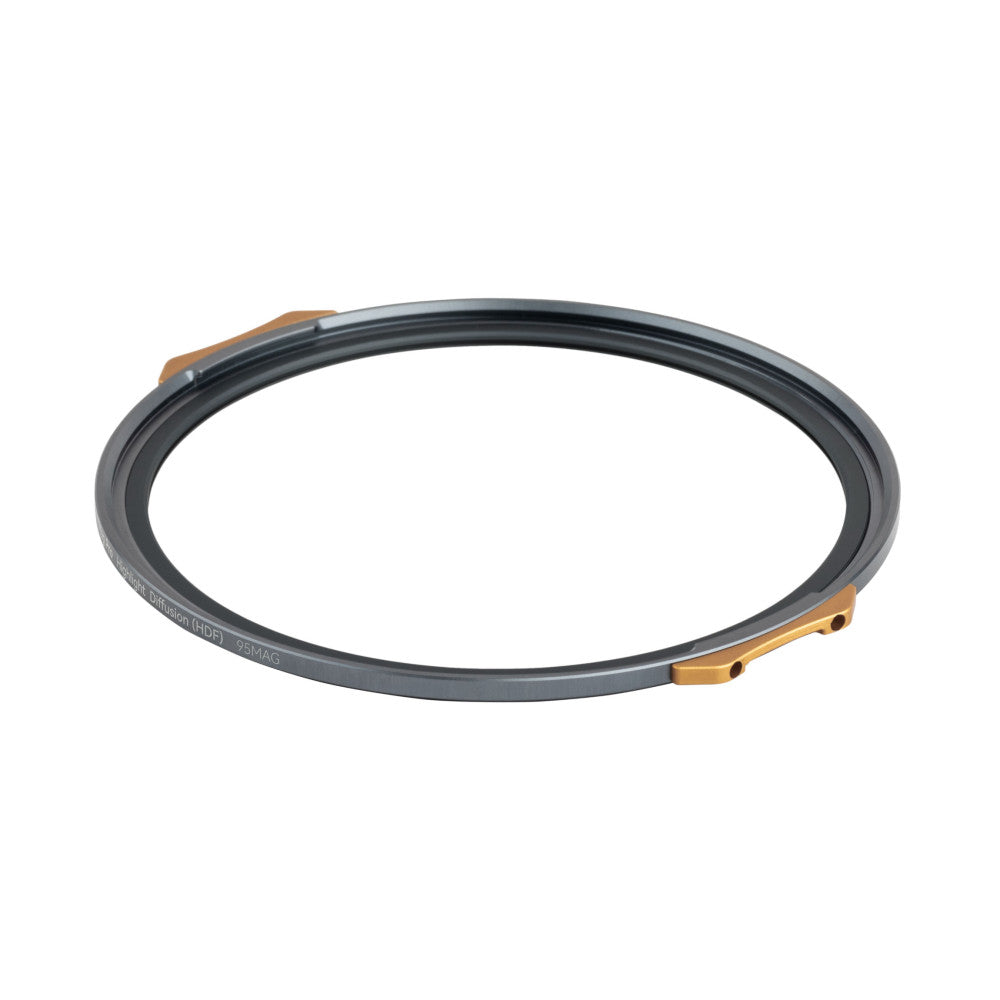 Angled overhead view of a circular dark gray filter ring with bronze magnetic attachment points on opposite sides.