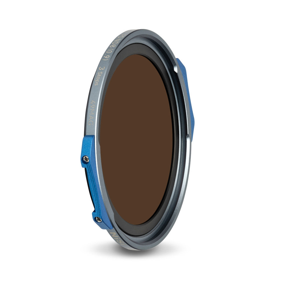 Angled view of a circular magnetic filter with blue side clips, dark tinted glass center, and gray metal ring with engraved text.