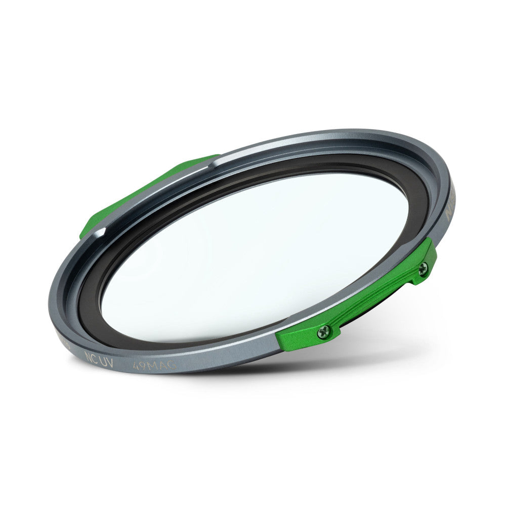 Angled view of a circular magnetic filter with gray metal ring, black inner gasket, green magnetic clips, and clear glass center against white background.