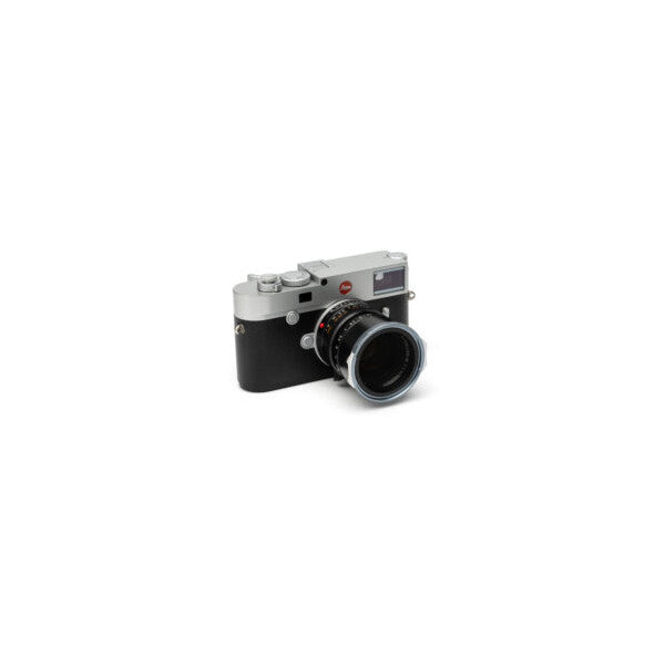 Vintage rangefinder camera with black body and silver top plate, shown from front-left angle against white background.