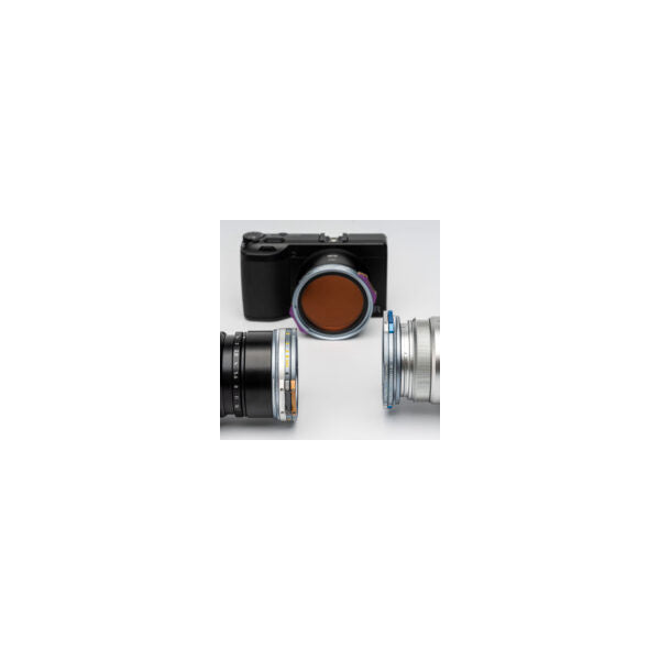 Flat lay view of NiSi JetMag Pro magnetic filter system showing black camera body with amber-toned filter attached, flanked by two silver lens adapters on white background.