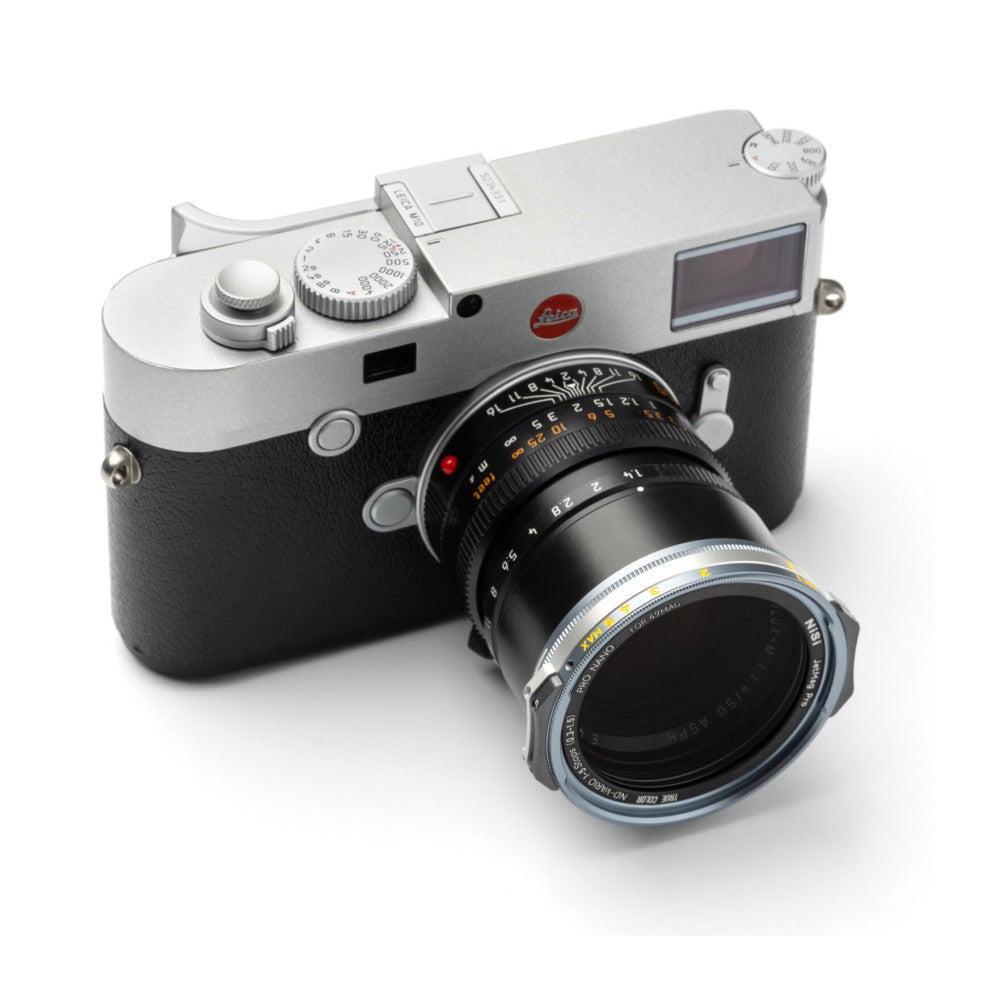 Leica rangefinder camera with black leather body and silver top plate, equipped with a telephoto lens, shown at three-quarter angle against white background.