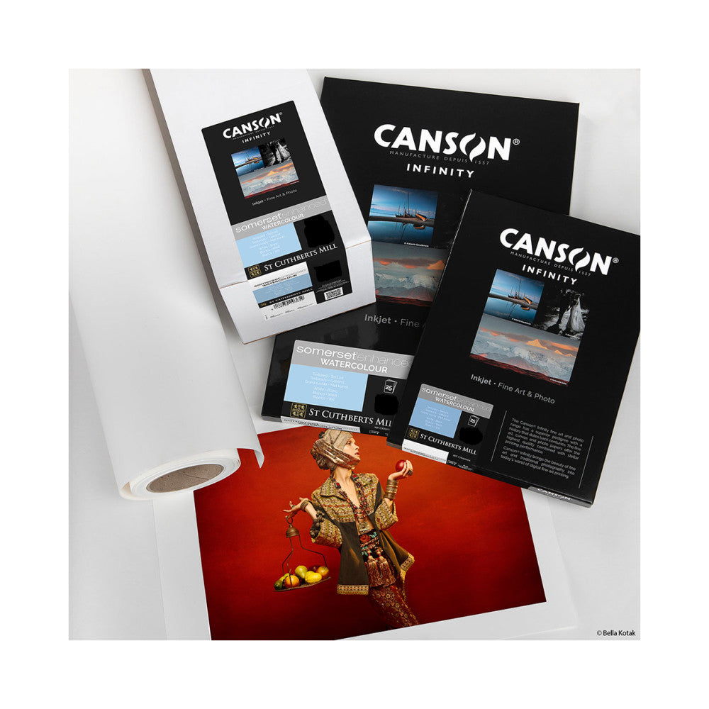Canson Infinity product packaging and Somerset Watercolour paper samples displayed with printed artwork on red background, overhead view.