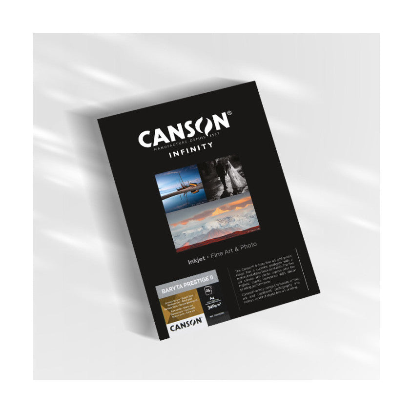 Angled front view of Canson Infinity Baryta Prestige II product packaging box on white background, showing black cover with brand logo and sample images.
