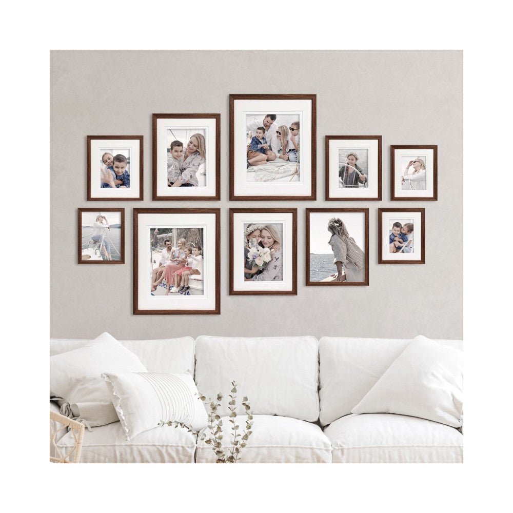 Ten chestnut-framed photos displayed on a beige wall above a white sofa, showing family portraits in various sizes arranged in a gallery wall layout.