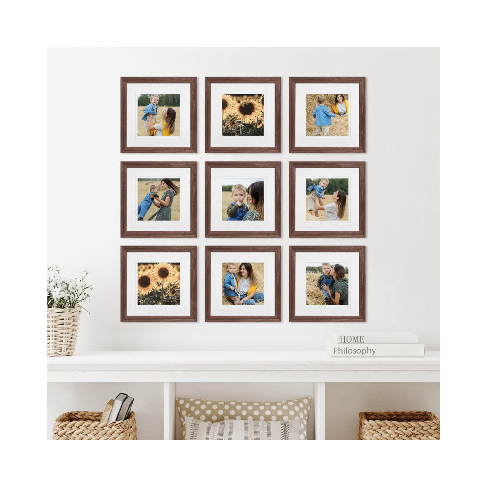 Nine brown wooden frames with white mats displaying family photos arranged in a 3x3 grid on a white wall above a shelf.