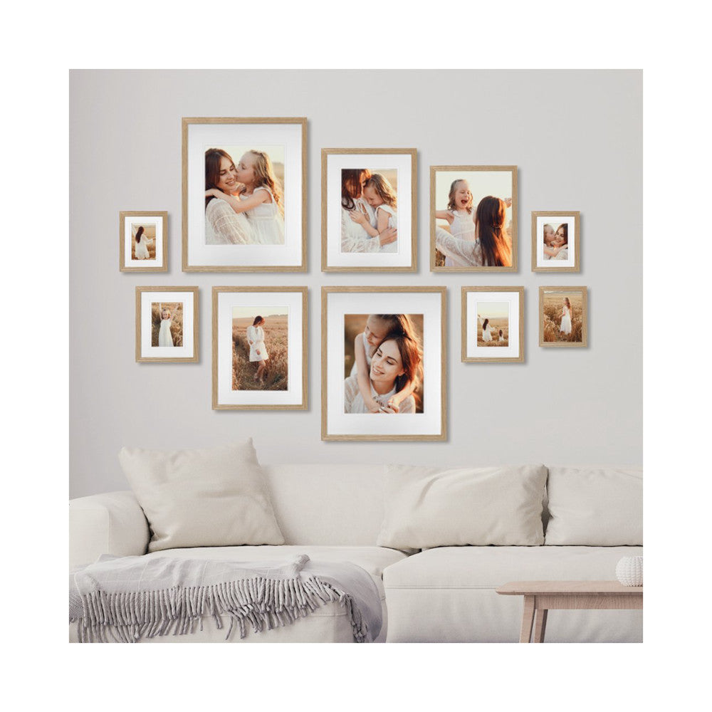 Gallery wall of ten natural oak frames displaying family photos arranged above a white sofa in a living room setting.