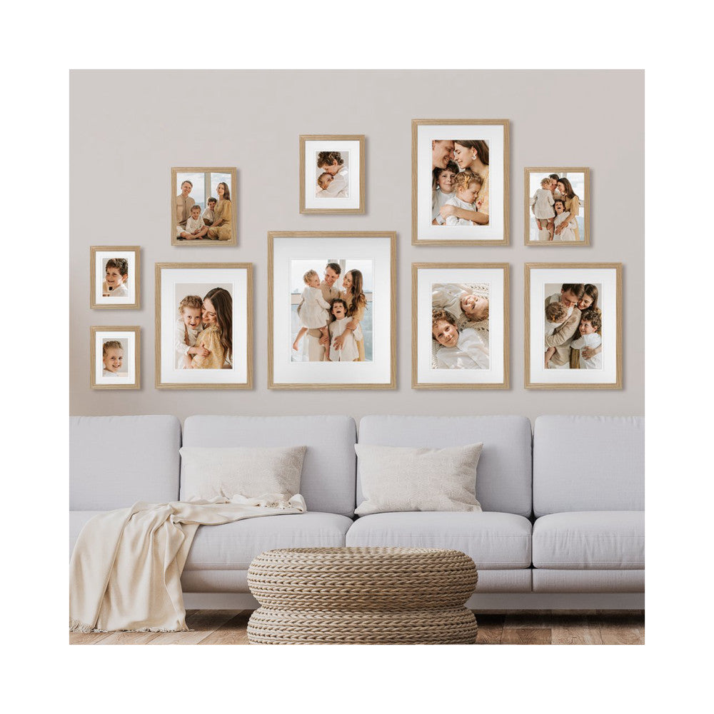 In-use view of wooden gallery wall frames displaying family photos above a gray sofa with decorative pillows and woven ottoman.