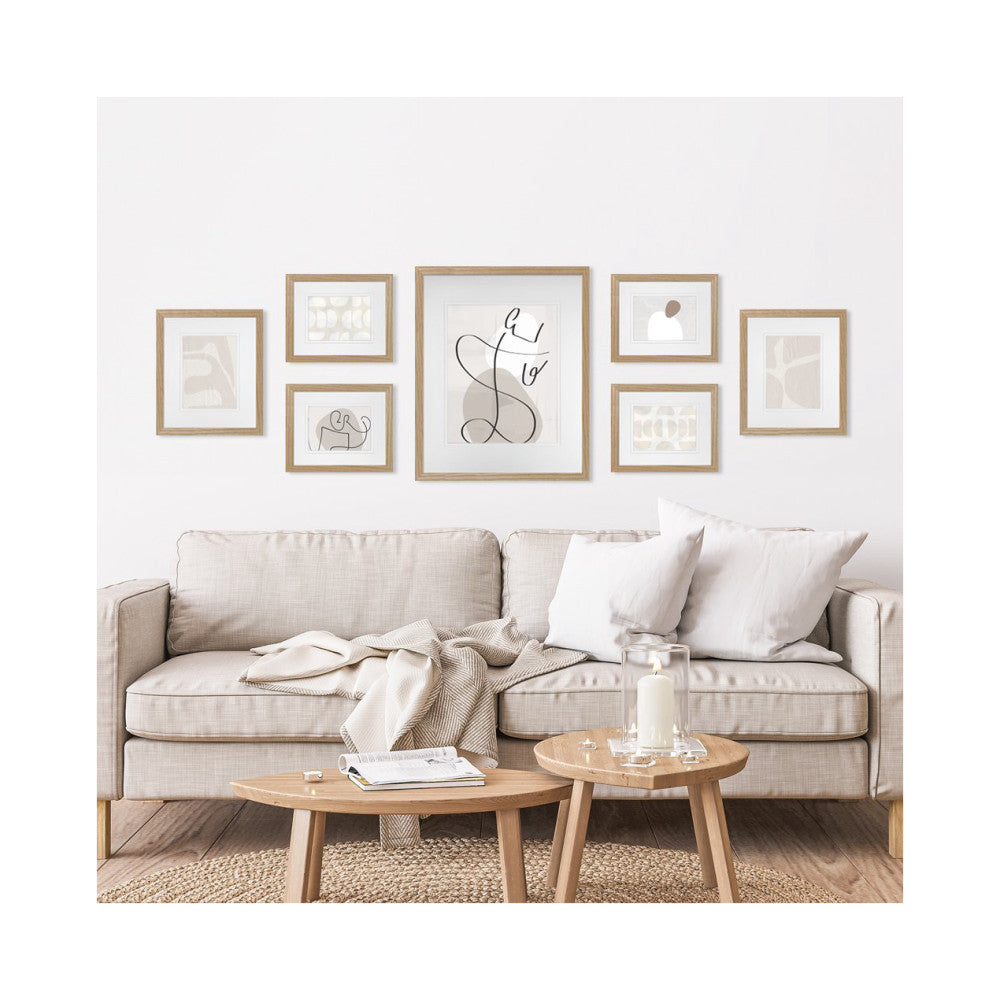 Seven natural oak frames displayed on a living room wall above a beige sofa with wooden coffee tables below.