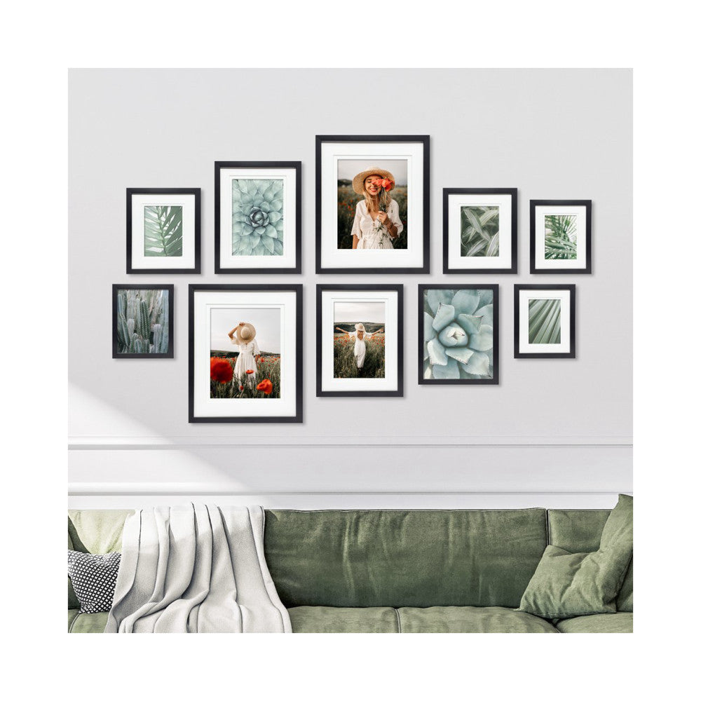 Gallery wall display with 10 black frames arranged above a green sofa, featuring botanical and portrait photography in various frame sizes.