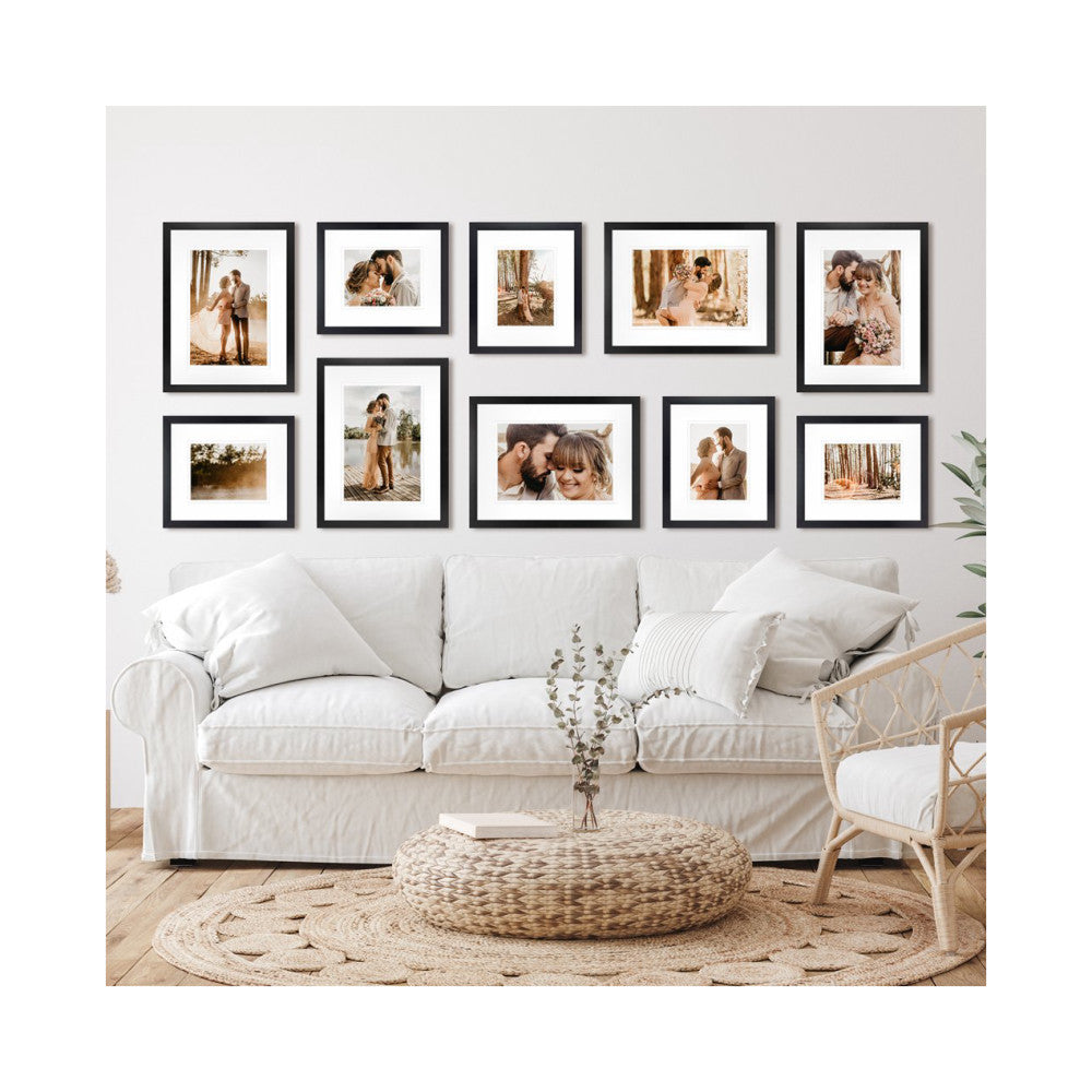 Black gallery wall frames displaying family photos above a cream sofa in a modern living room setting.