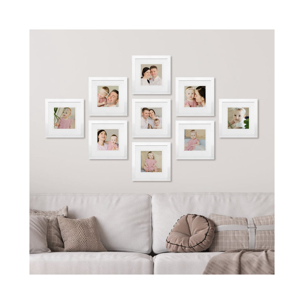 Nine white gallery frames displaying family photos arranged on a light wall above a beige sofa with decorative pillows.